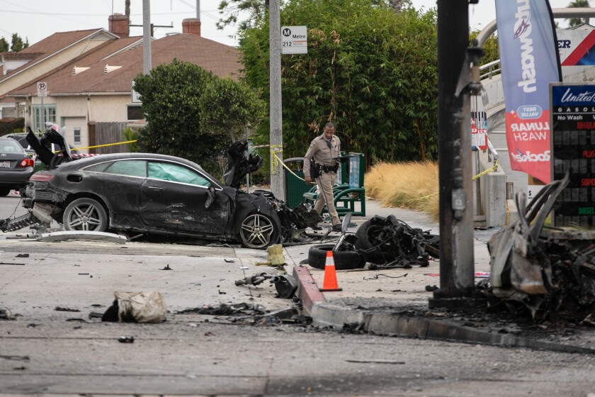A CHP officer walks past burned wreckage of vehicles near a gas station after a crash