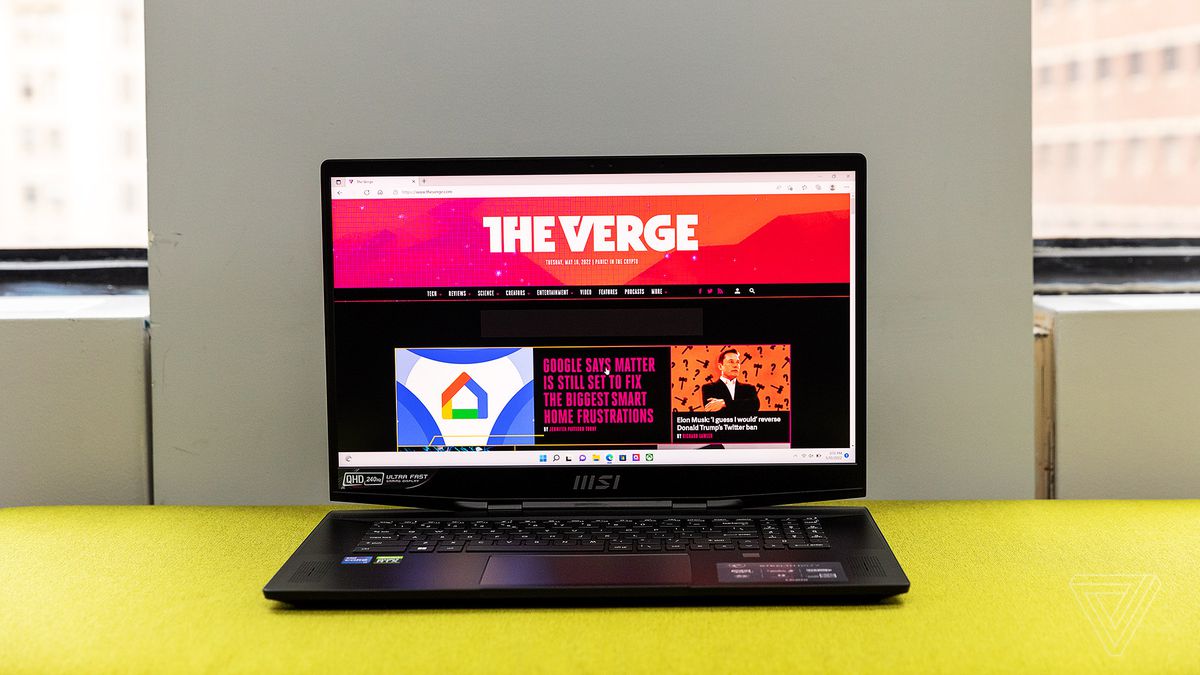 The MSI GS77 Stealth on a yellow fabric bench. The screen displays The Verge homepage.