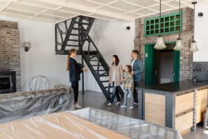 A family of three standing in front of a real estate agent.