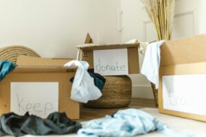 Cardboard boxes labeled keep, donate, and trash, filled with clothes while sortingitems before a move.